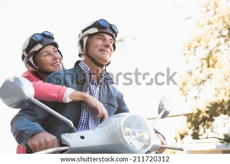 Happy senior couple riding a moped on a sunny day