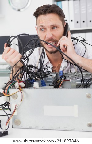 Angry computer engineer making a call in his office