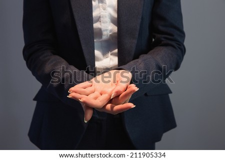 Businesswoman in suit holding her hands out on grey background