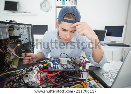 Computer engineer working on broken console with laptop in his office