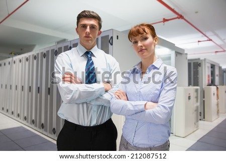 Confident data technicians looking at camera in large data center