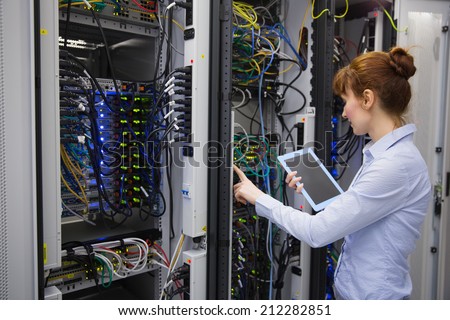 Technician using tablet pc while analysing server in large data center