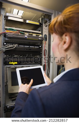 Pretty technician using tablet pc while fixing server in large data center