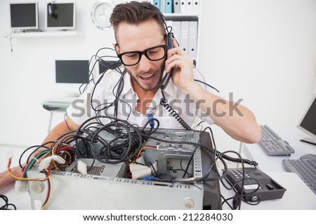 Angry computer engineer making a call in his office
