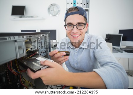 Smiling computer engineer working on broken console with screwdriver in his office