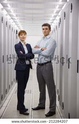 Team of computer technicians smiling at camera in large data center