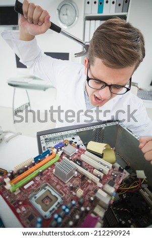 Computer engineer holding hammer over broken console in his office