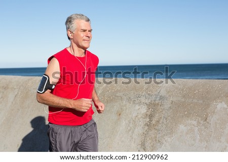 Active senior man jogging on the pier on a sunny day