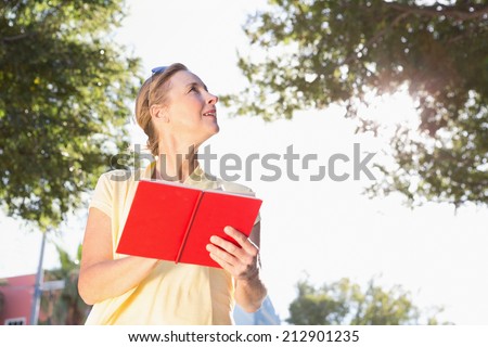 Blonde woman using her guide book on a sunny day
