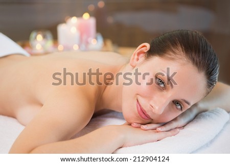 Side view portrait of a beautiful young woman lying on massage table at spa center