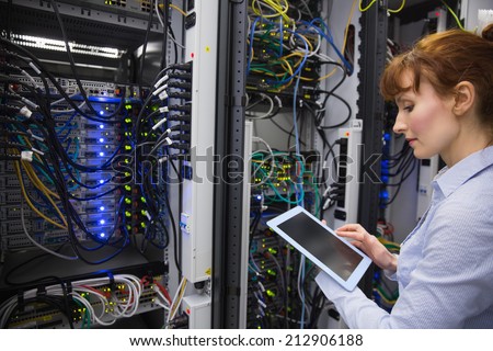 Technician using tablet pc while analysing server in large data center