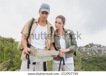 Hiking young couple looking at map on mountain terrain