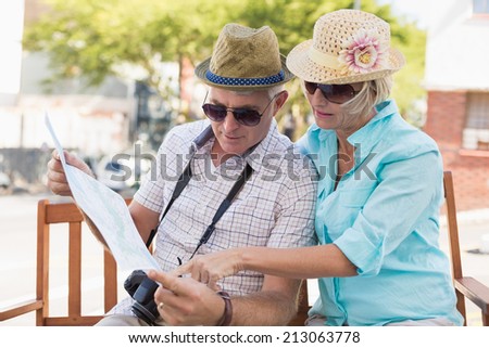 Happy tourist couple looking at map in the city on a sunny day