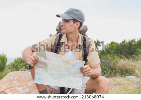 Portrait of a hiking man sitting with map on mountain terrain