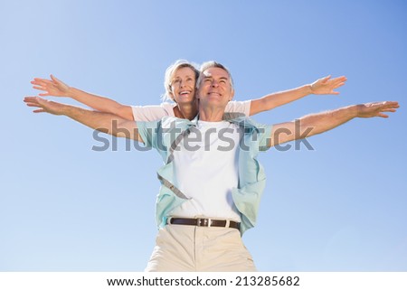 Happy senior man giving his partner a piggy back on a sunny day