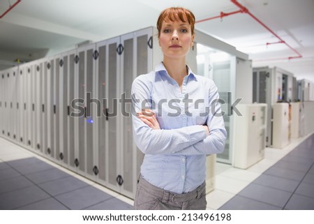 Serious data technician looking at camera in large data center