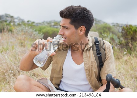 Portrait of a hiking man drinking water on mountain terrain
