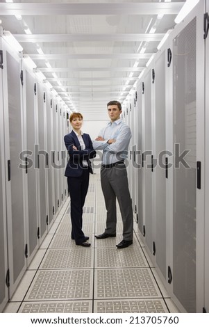 Team of computer technicians smiling at camera in large data center