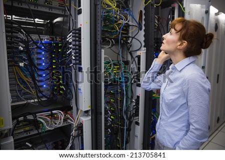 Technician talking on phone while analysing server in large data center