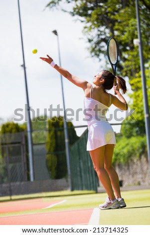 Pretty tennis player about to serve on a sunny day