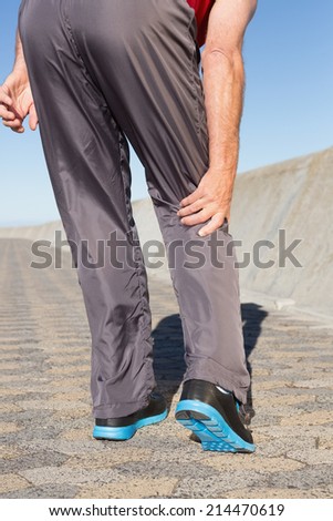 Active senior man touching his injured knee on a sunny day