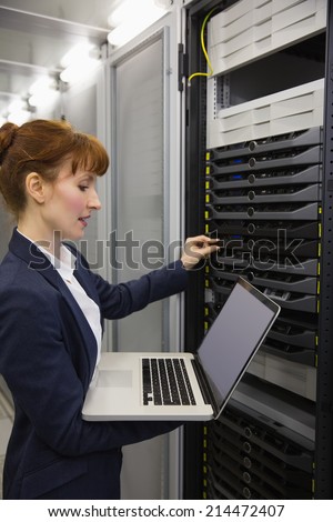 Pretty technician using laptop while working on servers in large data center