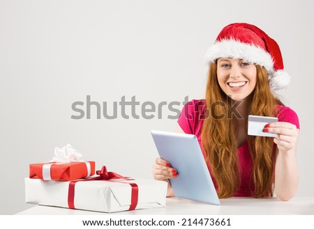 Festive redhead shopping online with tablet on white background