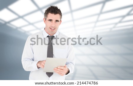 Portrait of a businessman with a tablet computer against white room with windows at ceiling