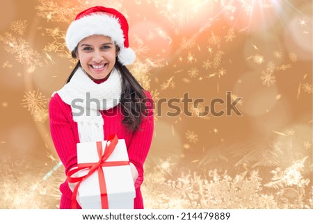 Festive brunette holding gift against cream snow flake pattern design