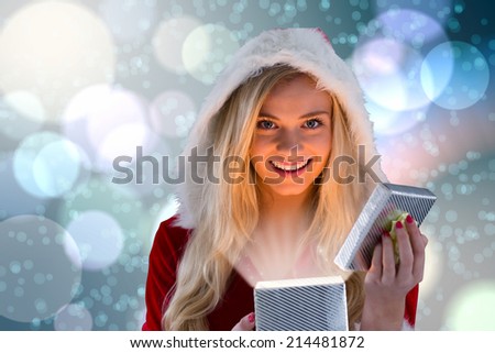 Sexy santa girl opening gift against light glowing dots on blue