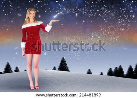 Pretty girl presenting in santa outfit against snow falling on fir tree forest