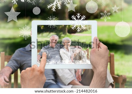Hands holding tablet pc against senior couple sitting on a bench