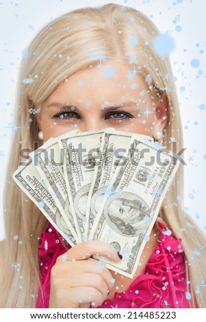 Blonde hiding her face with dollars banknotes against snow falling