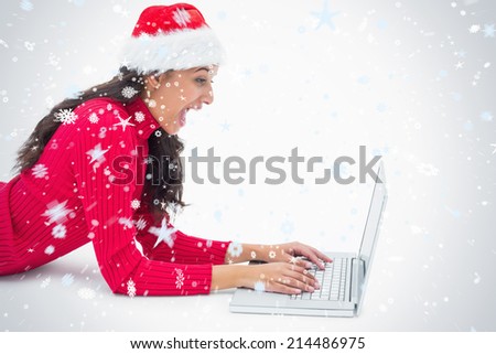 Beautiful festive woman typing on laptop against snow falling