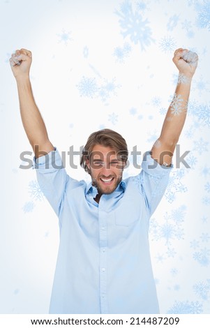Happy man celebrating success with arms up against snow falling