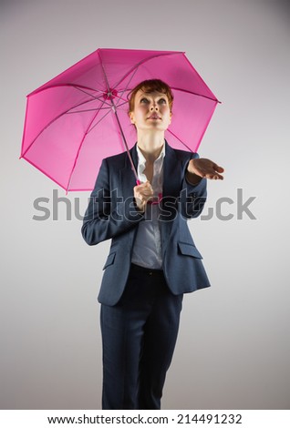 Smiling businesswoman holding pink umbrella on grey background