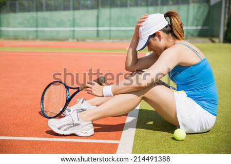 Upset tennis player sitting on court on a sunny day