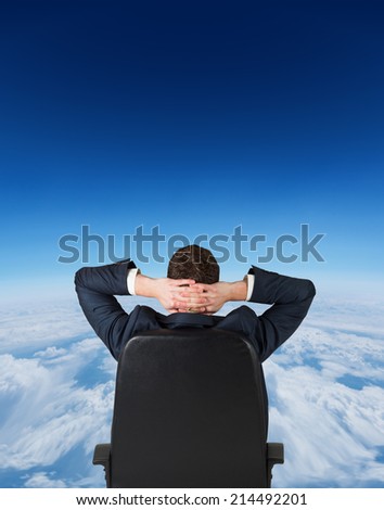 Businessman sitting in swivel chair against blue sky over clouds at high altitude