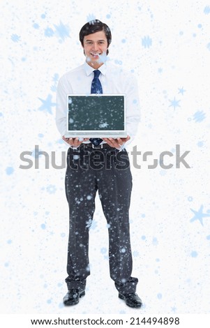 Smiling tradesman presenting screen of his laptop against snow falling