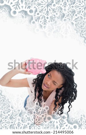 Woman looking inside her piggy bank against snowflakes on silver