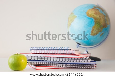 Stack on notepads on table with a globe behind them