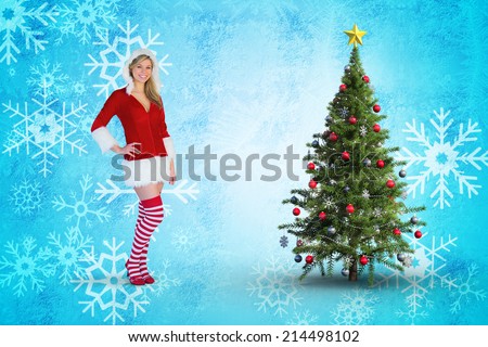Pretty girl smiling in santa outfit against blue snow flake pattern design