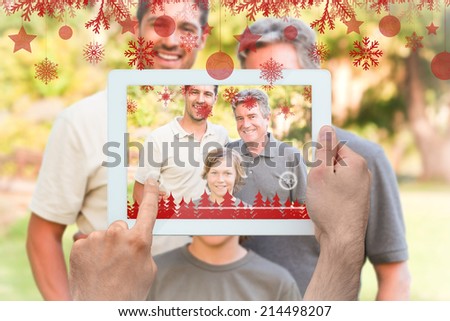 Hands holding tablet pc against family looking at the camera in the park