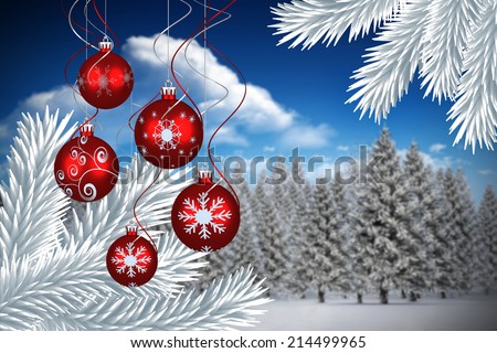 Digital hanging christmas bauble decoration against fir tree forest in snowy landscape