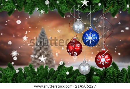 Digital hanging christmas bauble decoration against fir tree in snowy landscape