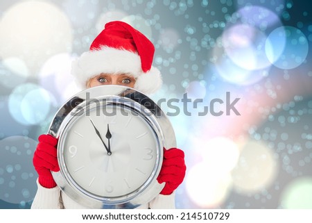 Festive woman holding clock against light glowing dots on blue