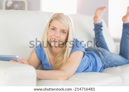 Portrait of a relaxed beautiful young woman using digital tablet in the living room at home