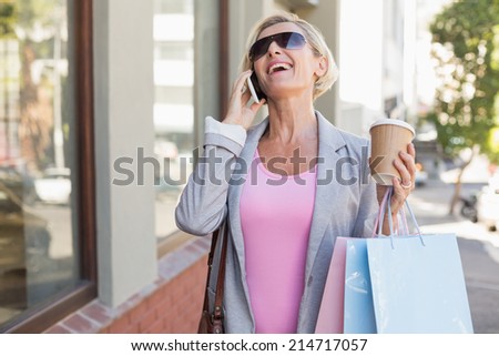 Happy mature woman walking with her shopping purchases on a sunny day