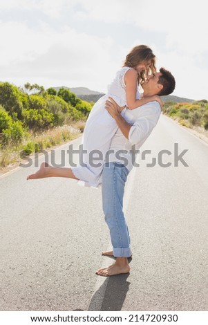 Side view of a young man carrying woman on countryside road