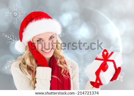 Happy festive blonde with gift against silver snow flake pattern design